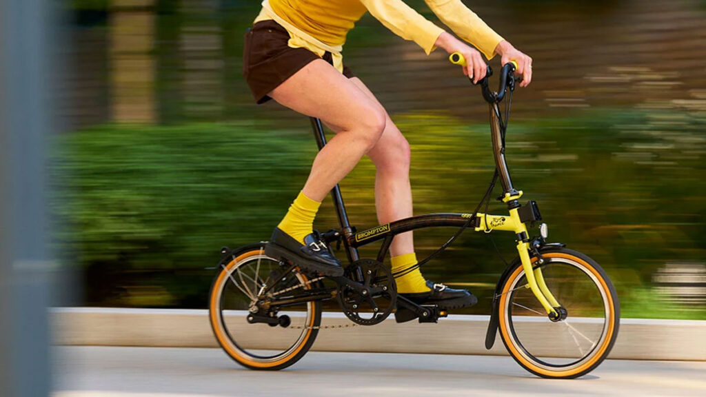 Brompton Tour de France C Line trifold bike with black frame, yellow accents, and race-day photography print