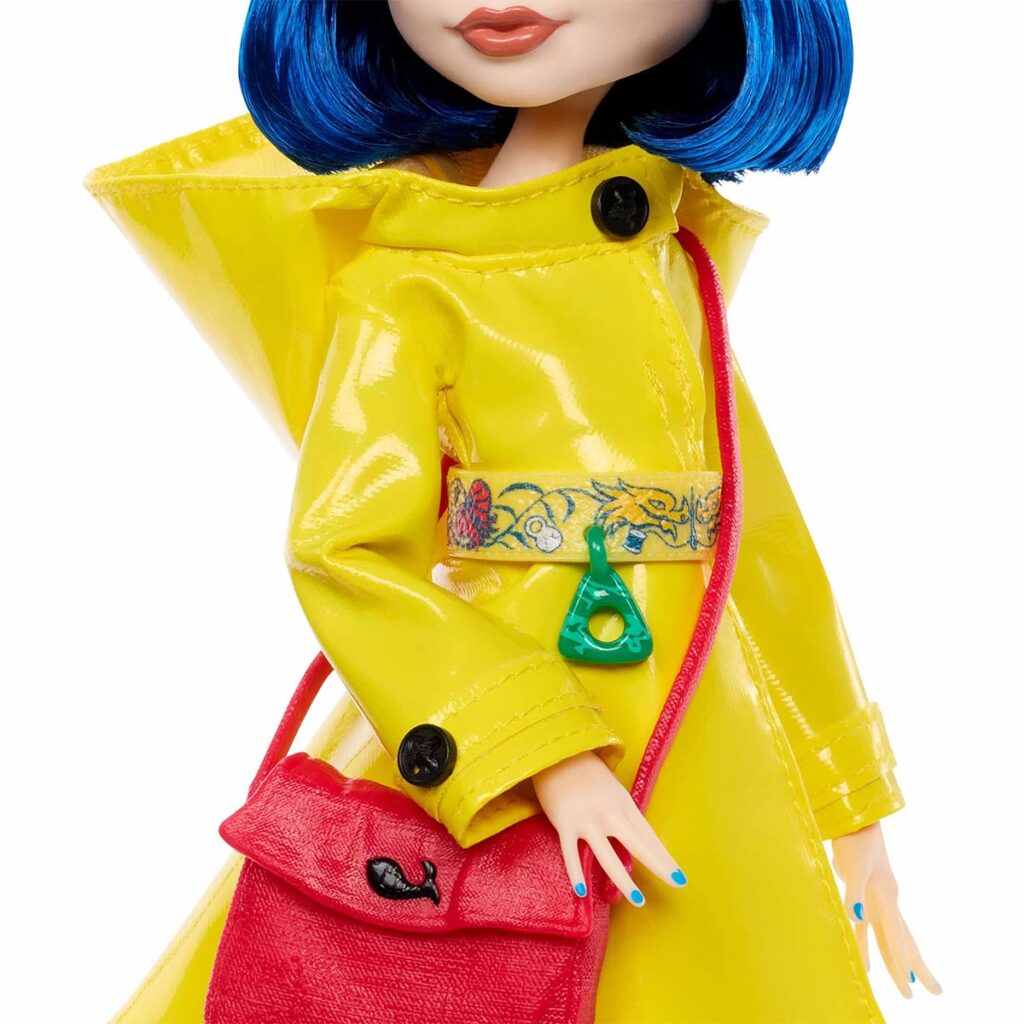 Monster High Skullector Coraline doll wearing yellow raincoat with rag doll and cat accessories