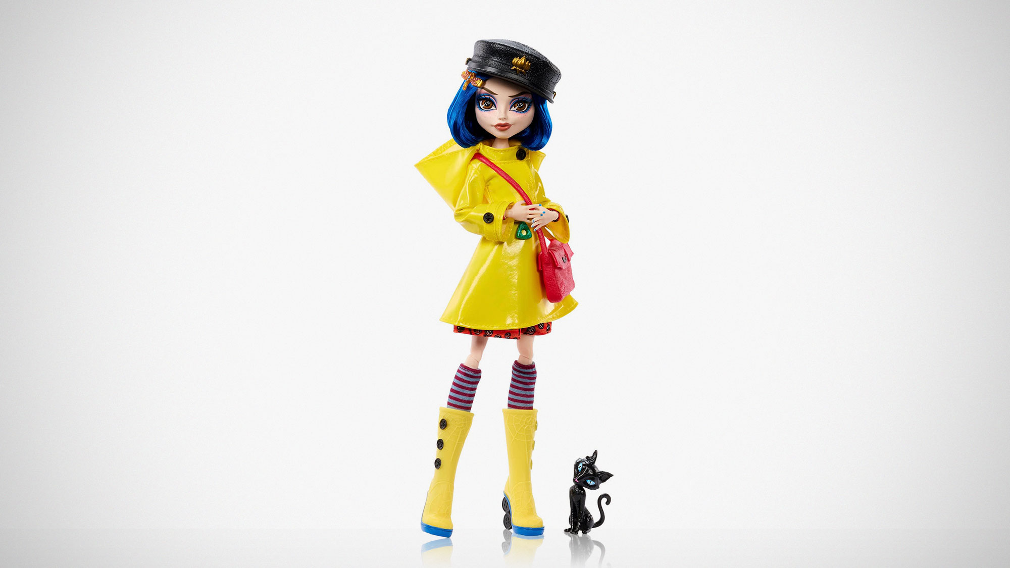 Monster High Skullector Coraline doll wearing yellow raincoat with rag doll and cat accessories